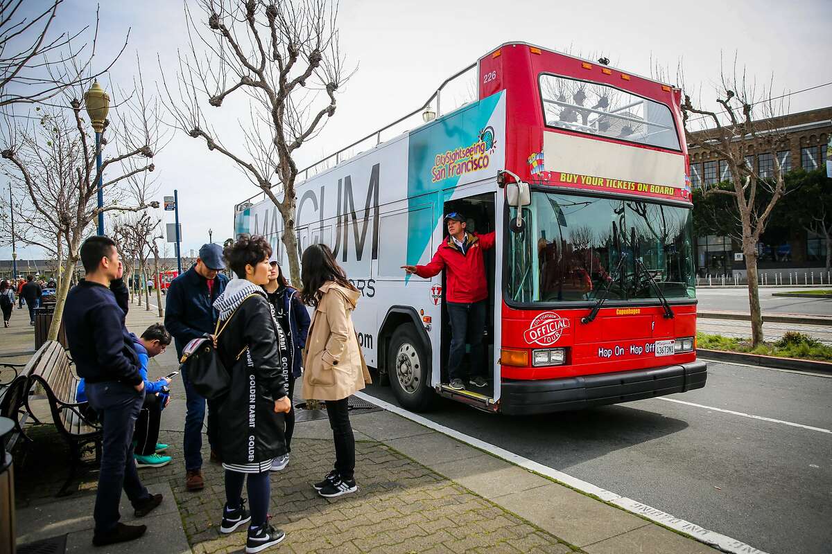 Tour guide Rey Zegri (right,red jacket) hops off a City Sightseeing bus tour to make a stop and chat with customers in San Francisco, California, on Wednesday, Feb. 22, 2017.
