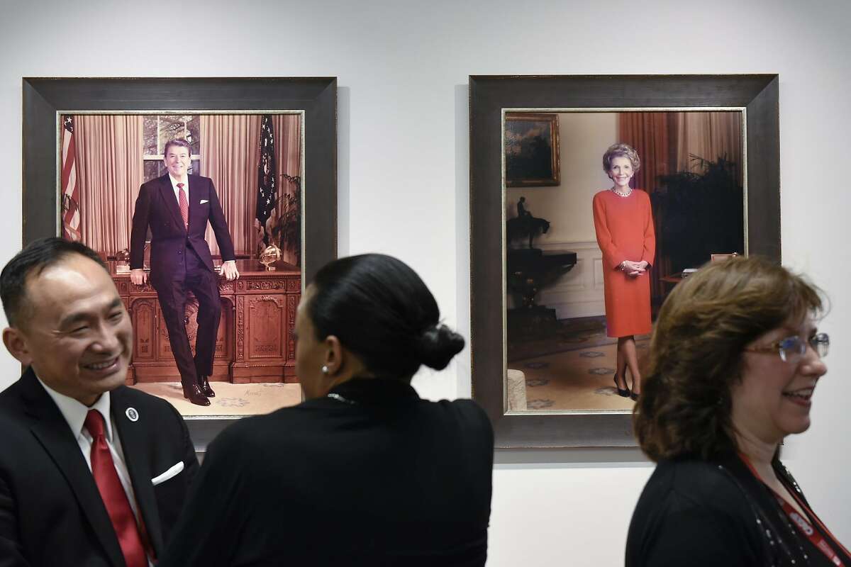 Convention-goers chat in front of portraits of Ronald and Nancy Reagan at the California Republican Party headquarters in Sacramento.