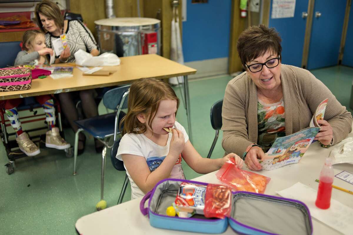 Chestnut Hill third-grader Jillian Mohr, from left, reads with Christie Hill while first-grader Kyra Bensal eats her lunch and listens to Ann Craig read aloud during the Big Brothers Big Sisters Lunchbox Learners program Wednesday afternoon. Thirteen volunteers from Big Brothers Big Sisters sat with students, primarily in first through third grade, once a week for an hour to help students practice reading.