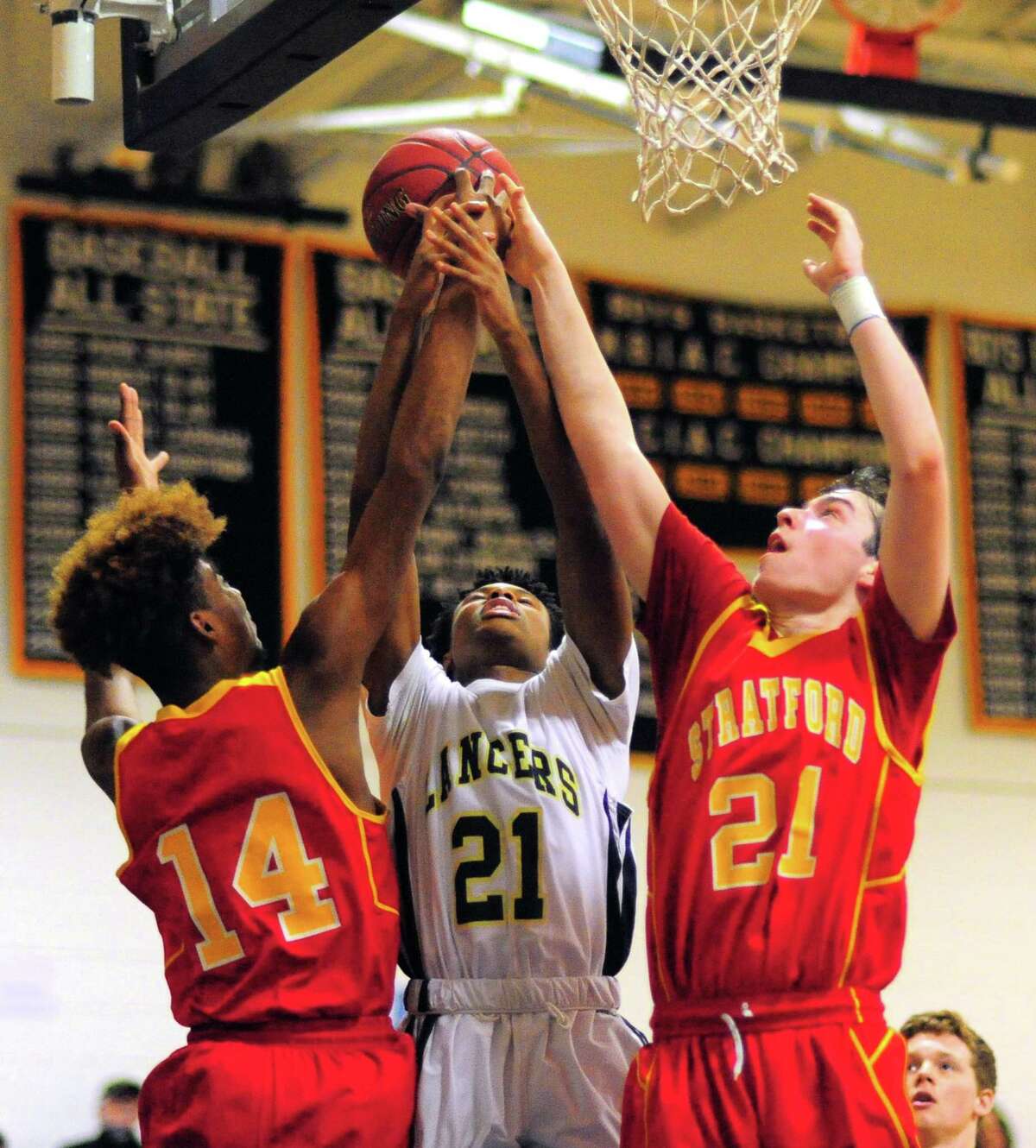 Notre Dame of Fairfield’s Rodney Medor, center, fights for for a rebound with Stratford’s Prince Carter, left, and Jack Ryan, right, on Friday.