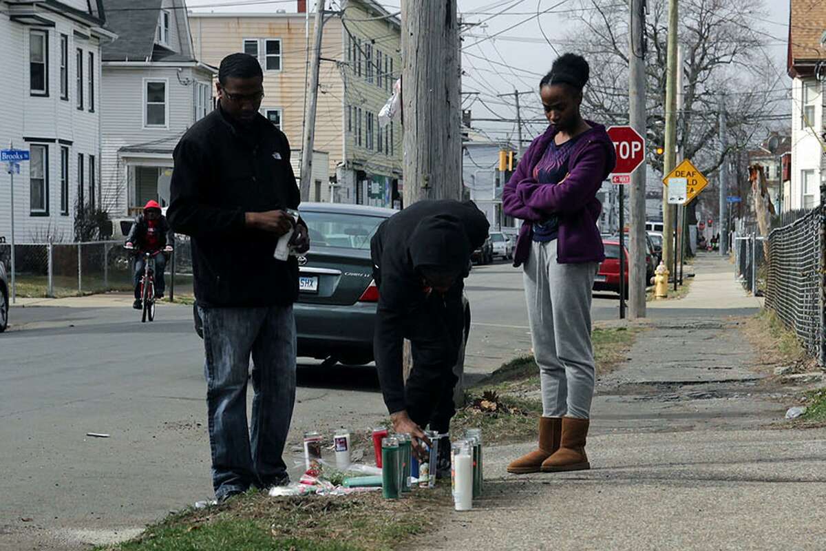 Mourners light a candle at the place where Michael Watkins, 26, of Bridgeport, was found fatally shot Friday night. Feb. 25, 2017, Bridgeport, Conn.