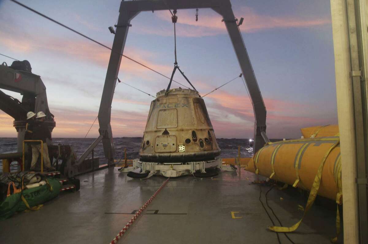 The SpaceX Dragon capsule sits aboard a ship in the Pacific Ocean west of Mexico's Baja Peninsula after returning from the International Space Station during a 2015 mission. SpaceX announced Monday it would send two paying customers to the moon next year on a private flight aboard its Dragon capsule. The company said the unnamed customers have paid a significant deposit for the moon trip