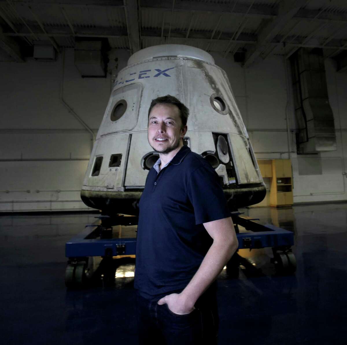 SpaceX founder Elon Musk stands in front of the SpaceX Dragon capsule at Space Exploration Technologies Corp. Musk wouldn’t identify the pair of private citizens who will go fly on next year’s moon mission or the price tag. They’ve already paid a “significant” deposit, he noted.