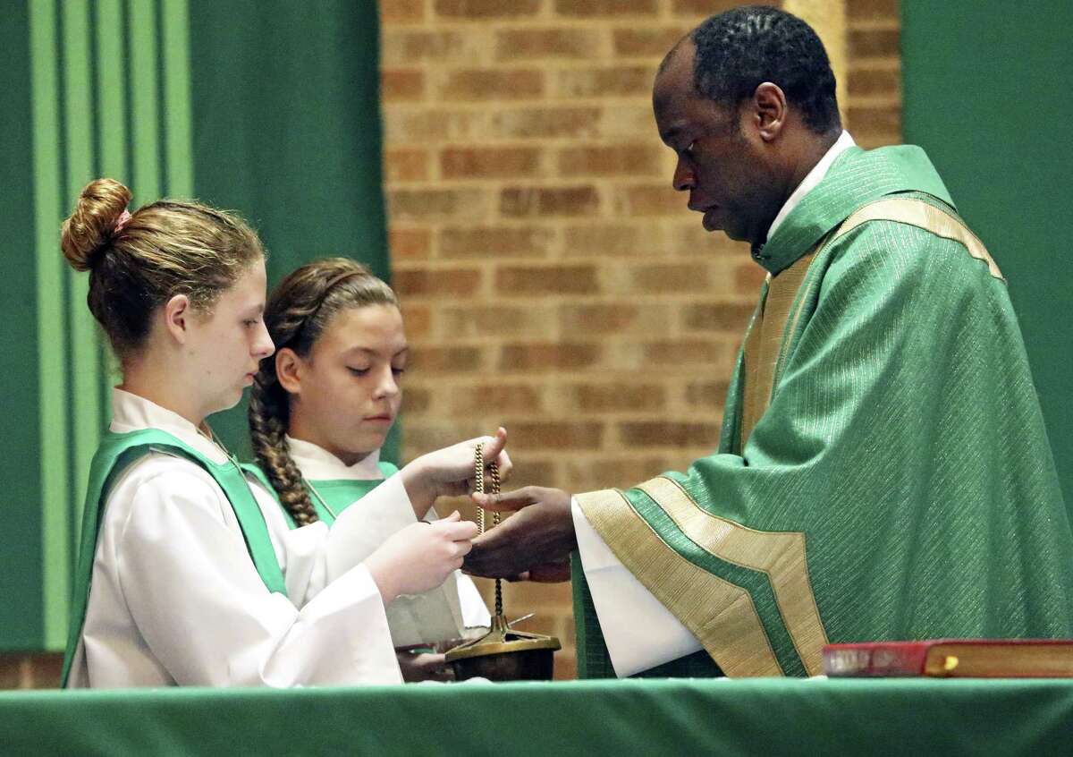 Madison (left) and Allison Hopcus assist Father Fidele as altar servers.