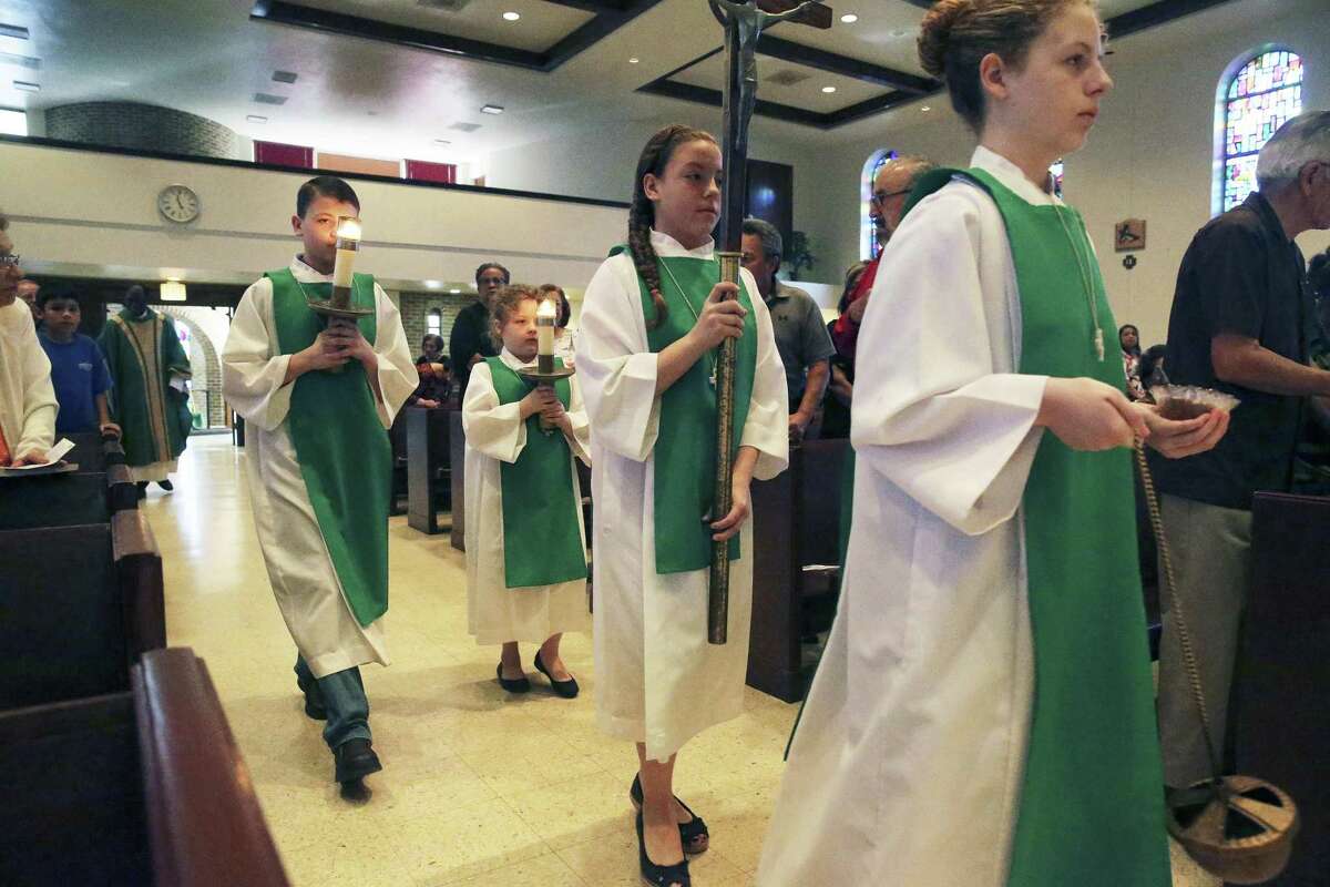 The older sibling, Madison, leads the way in while Tyler (from left), Brooke and Allison follow as the Hopcus kids approach the altar at St. John Berchmans Catholic Church. Regular parishioners are cheered by the sight of the family’s service.