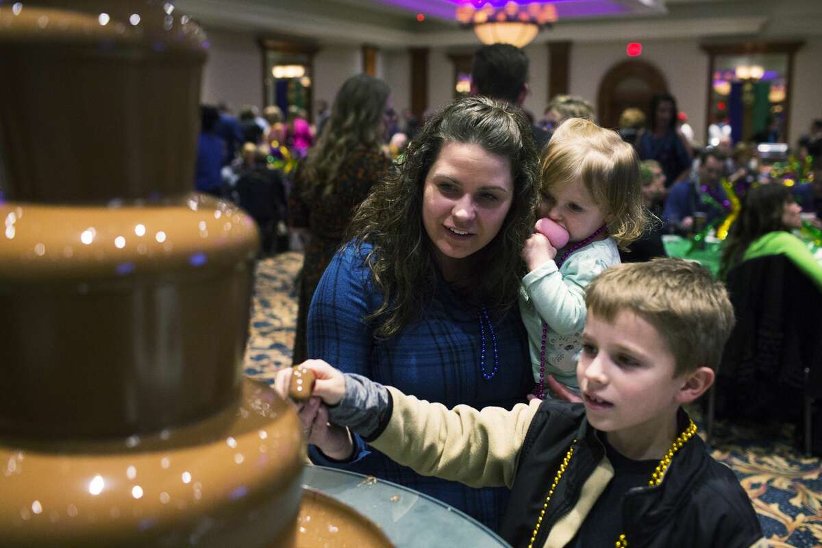 THEOPHIL SYSLO | For the Daily News Alicia Heading, and her children Clayton Heading, 8, and Gabrielle Heading, 2, enjoy snacks from a chocolate fountain provided by Heather 'n' Holly while participating in the Legacy Center's World's Greatest Mardi Gras Feast at The Great Hall Banquet on Tuesday.