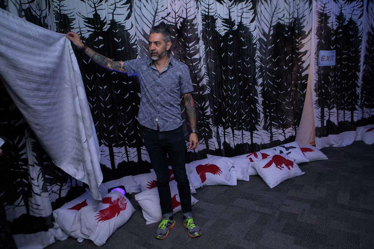 Artist Richard Armendariz pulls back a sheet to welcome guests into the bedsheet tent in "The Dream Keeper," his installation at the DoSeum.