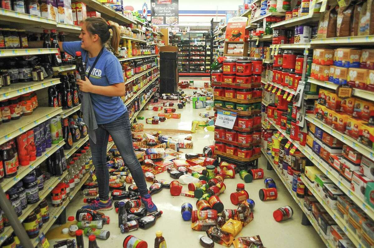 Employee Talia Pershall, 16, puts syrup back on a shelf while cleaning up at White's Foodliner grocery store Saturday, Sept. 3, 2016 in Pawnee, Okla., following a 5.6 magnitude earthquake that hit north-central Oklahoma.