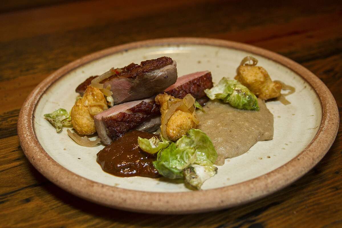 Smoked duck breast with house made mole negro, corn-benne fritters, pickled summer peppers and Brussels sprouts, from The Granary's dinner menu.
