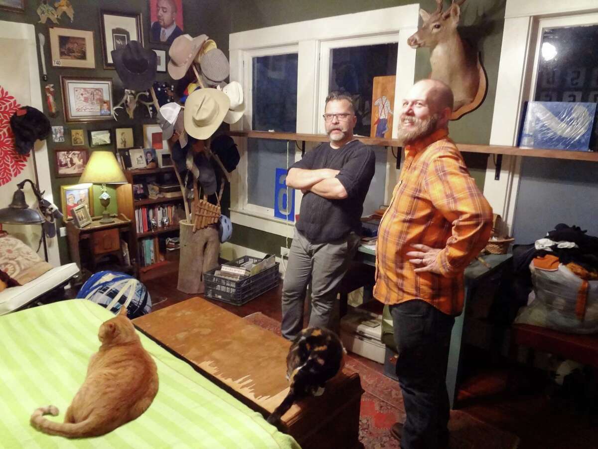 Rick Frederick and Chris Sauter, with cat Chuckie (named for the late SA aritst Churck Ramirez) on the bed, talk about the decor of their bedroom.