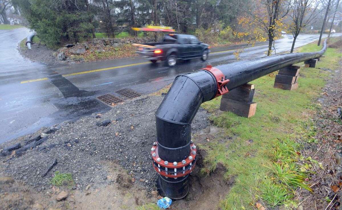 A vehicle passes by a pipe connected from Davenport Ridge Lane to Davenport Ridge Road in Stamford in November. Aquarion installed the pipe to bring 4 million gallons of water a day into Stamford from Bridgeport. The Stamford reservoirs are less than half what they should because of the drought.
