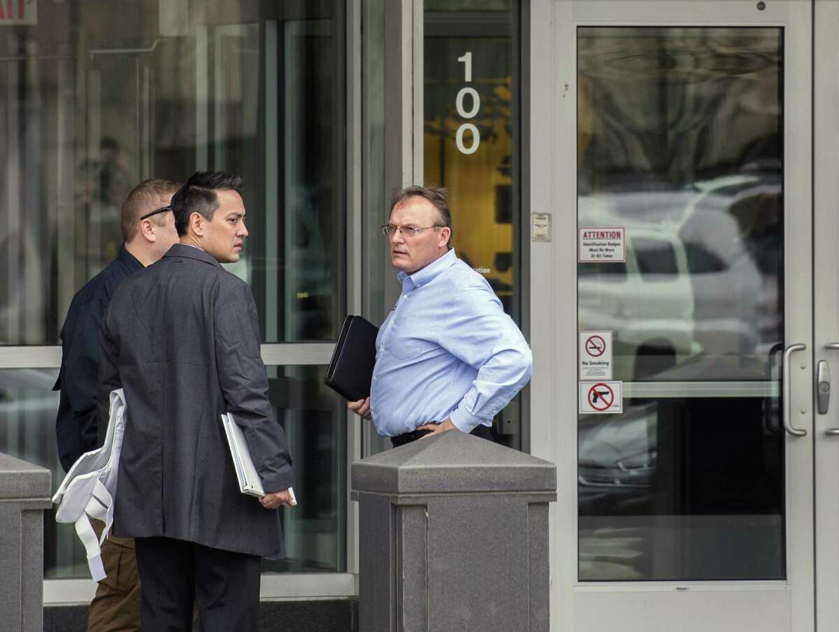 Steve Settingsgaard (right), head of North American security for Caterpillar, stands outside of the company’s world headquarters Thursday in Peoria, Ill., talking with two law enforcement officials. Federal law enforcement officials Thursday executed a search warrant at Caterpillar’s Peoria headquarters and a facility that ships parts overseas.