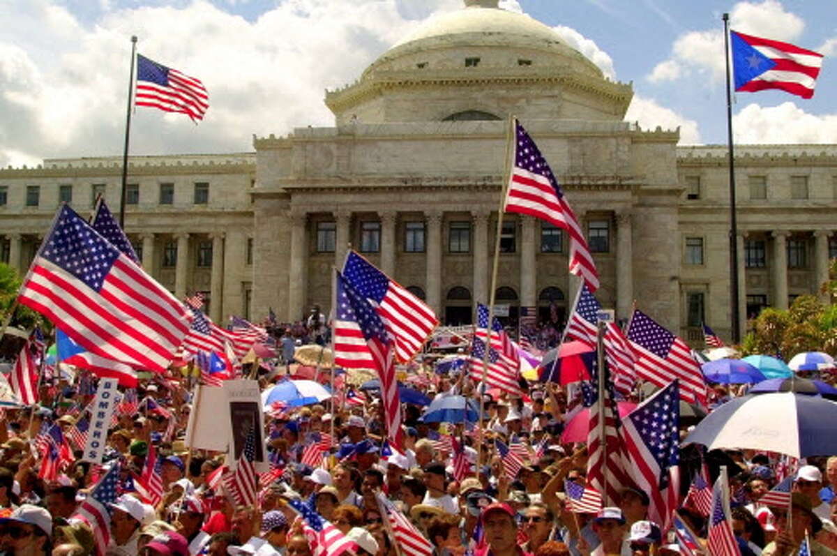 Thousands waves American flags during a rally celebrating U.S. Citizenship at the Capitol in San Juan, Puerto Rico Sunday, March 5, 2000. Puerto Ricans were granted U.S. citizenship by President Woodrow Wilson in 1917 through the Jones Act.