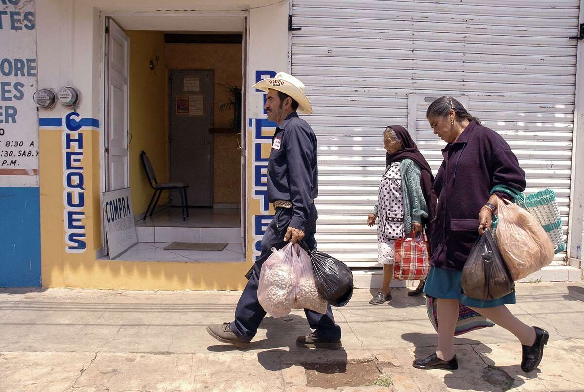 José Ortíz (center) carries groceries through Villa Morelos with his wife Josefina Chávez Pérez (right). Ortíz is one of about a half-dozen San Angel natives and former IFCO Sytems pallet builders in San Antonio who were rounded up in a immigration raids last month. He was wearing Texas Pallet overalls and a cowboy hat with “Texas Rodeo” embroidered on it. Such raids sow fear and will ultimately hurt Texas.
