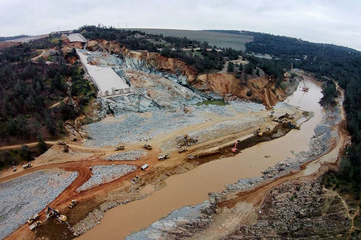 The damaged main spillway of the Oroville Dam is seen at the top left, as officials continue to work on clearing debris from the bottom on Friday, March 3, 2017, in Oroville, Calif.
