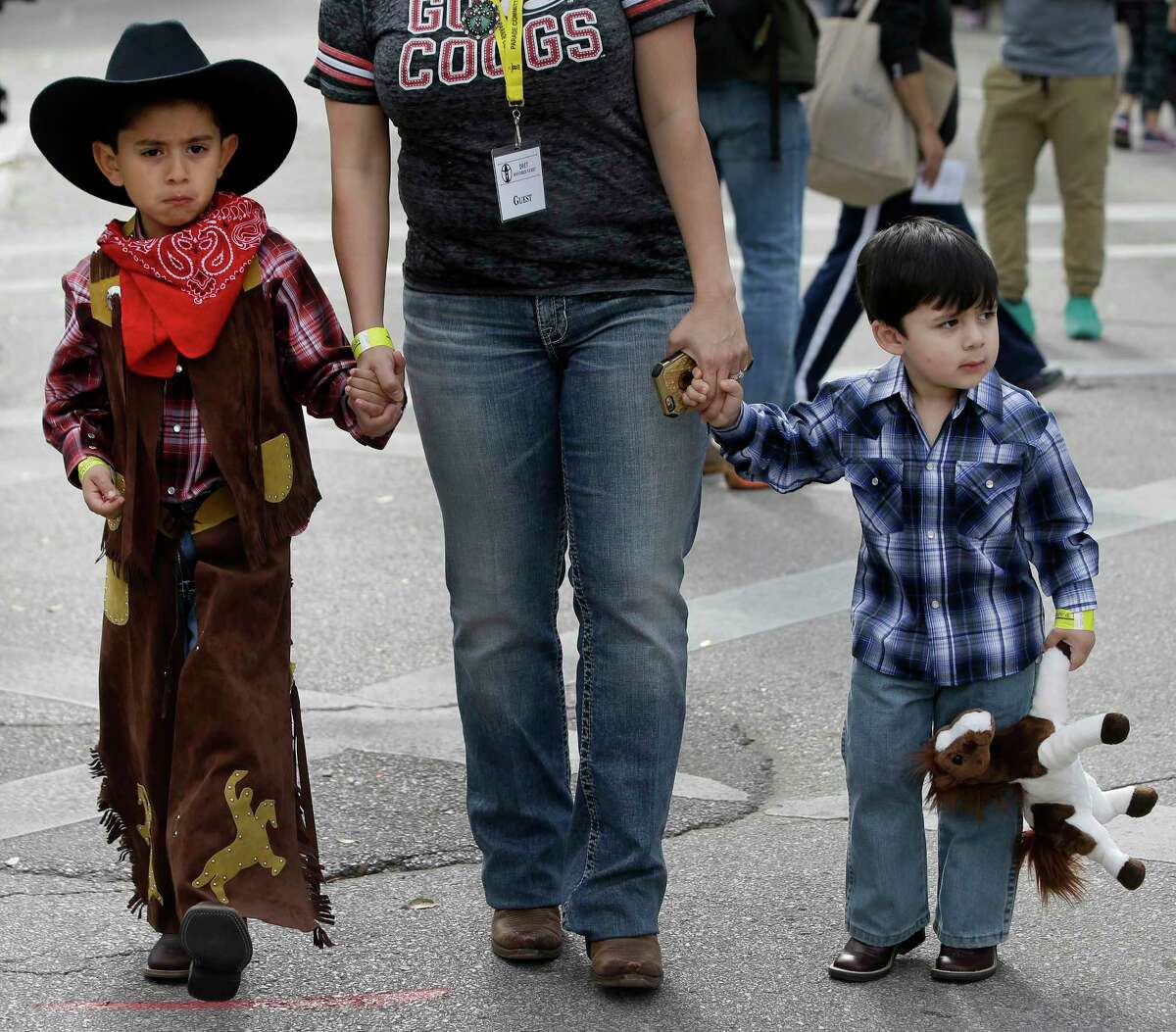 Brothers Armando Walle, left, 6 and Joaquin Walle, 3, walk with their mother, Debbie Walle, at the Houston Livestock Show and Rodeo Downtown Rodeo Parade Saturday, March 4, 2017, in Houston.