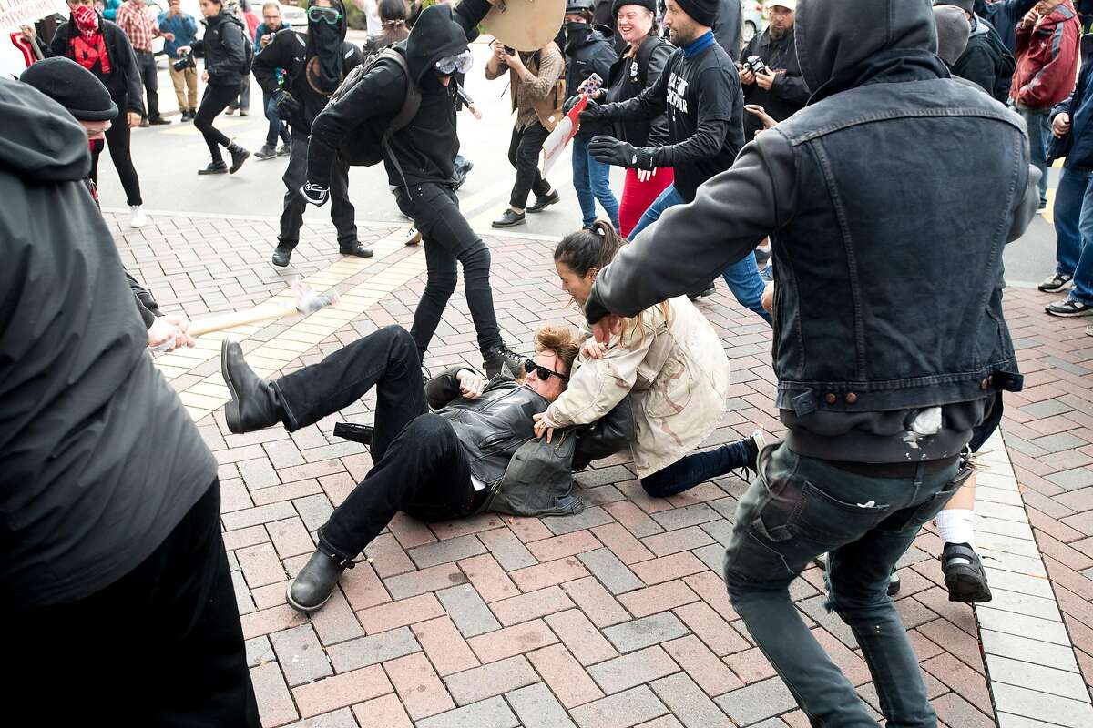 Black bloc protesters kick a man as demonstrators for and against President Donald Trump brawl in Berkeley, Calif., on Saturday, March 4, 2017.