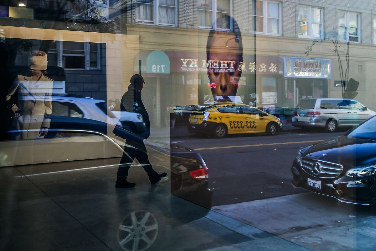 Ellis Street is reflected in the windows of Modernism gallery where paintings can be seen hung up on the walls in San Francisco, California, on Thursday, Feb. 23, 2017.