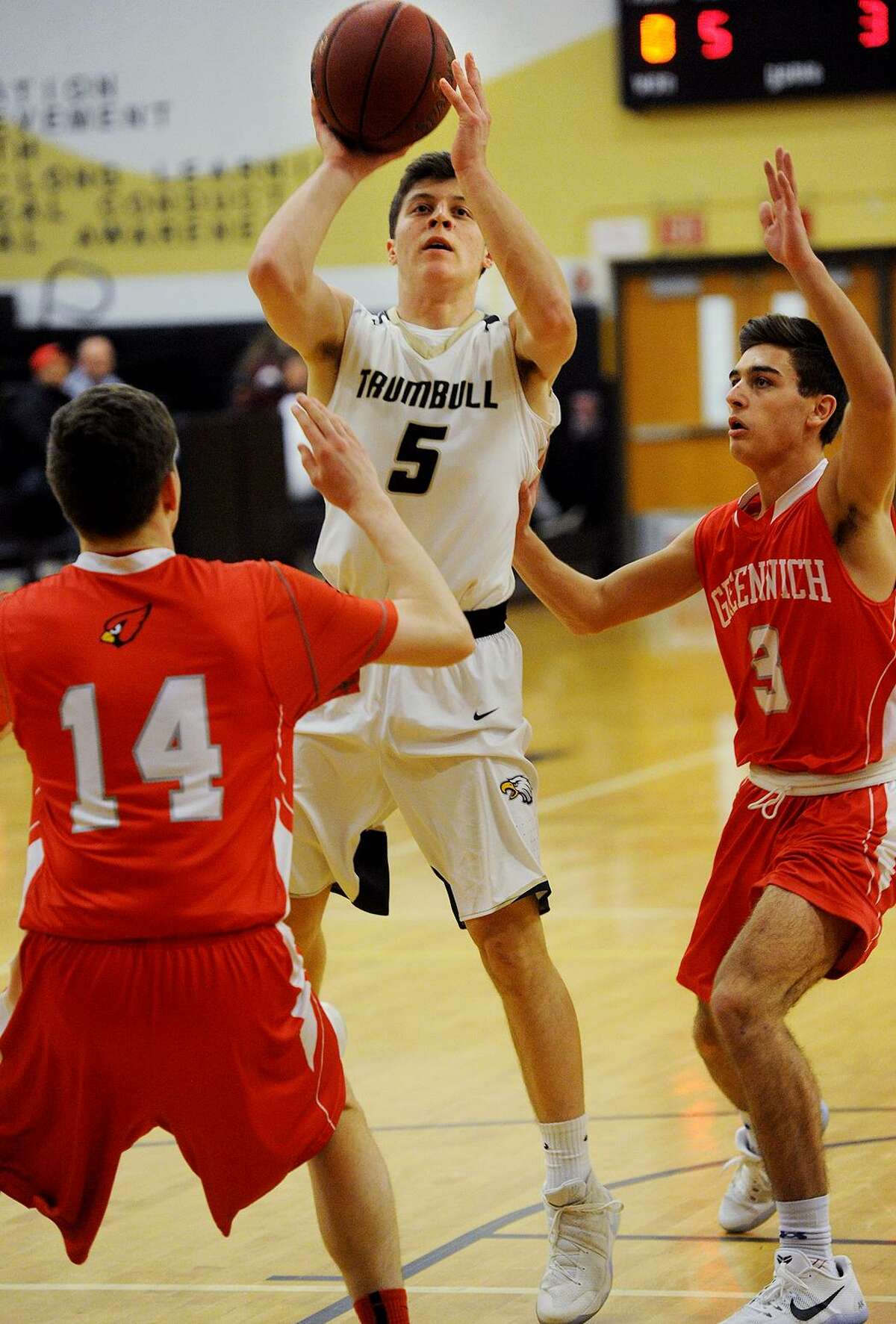 Trumbull’s Daniel Ruchalski takes a jump shot between Greenwich defenders Robert Clark, left, and Charlie Zeeve during his team's victory in the opening round of the Class LL tournament Monday at Trumbull High School.