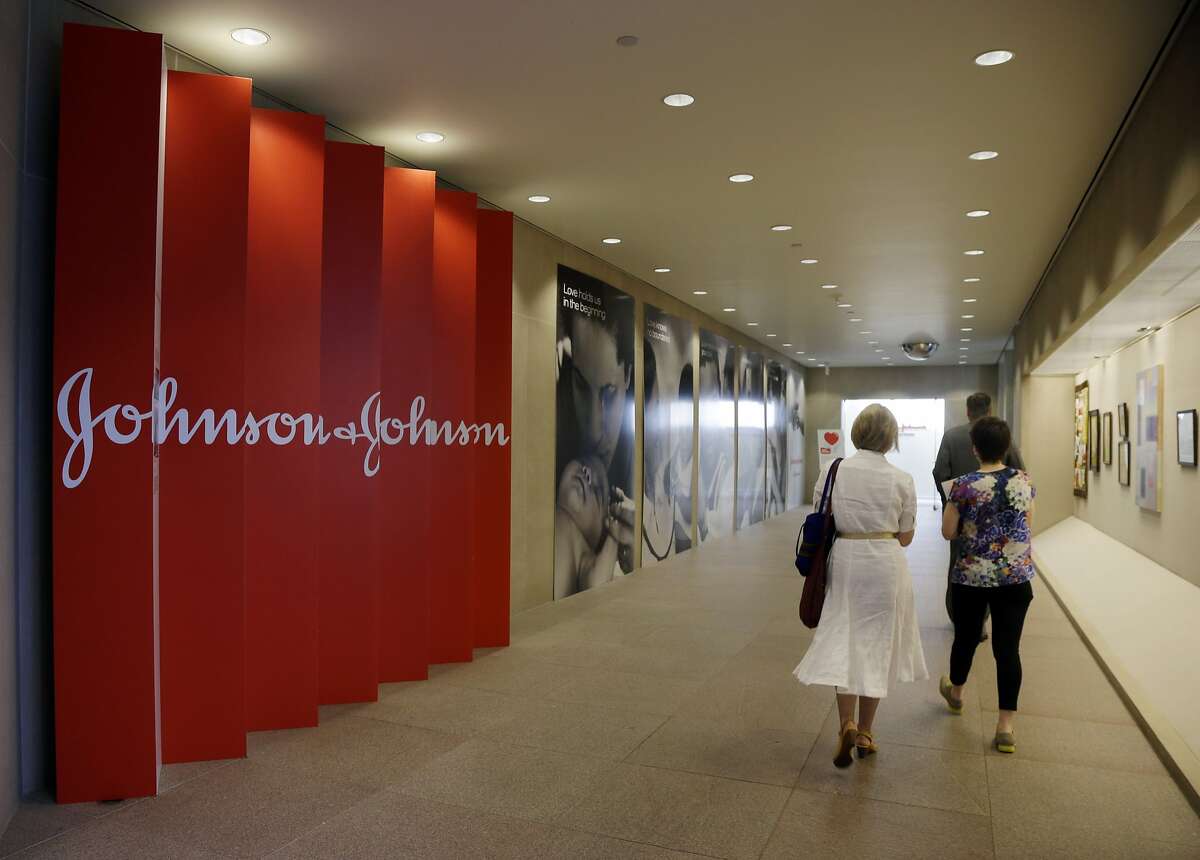 FILE - In this July 30, 2013, file photo, people walk along a corridor at the headquarters of Johnson & Johnson in New Brunswick, N.J. Several big drugmakers are trying to quell the ongoing furor over high drug prices by revealing more information about their pricing and even pledging to keep a lid on increases. The latest drugmaker move came Monday, Feb. 27, 2017, when Johnson & Johnson, the world's biggest maker of health care products, issued its first public report on price increases for its drugs. (AP Photo/Mel Evans, File)