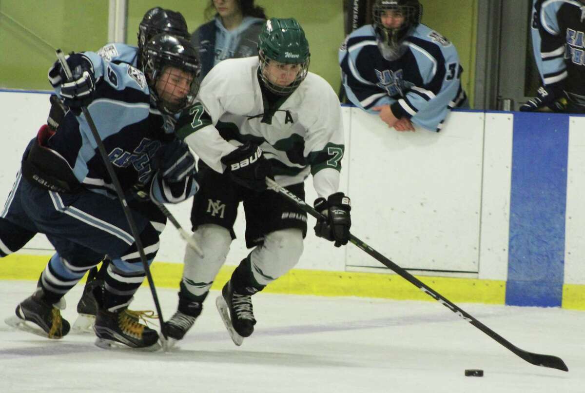 Senior Thomas Schneider, right, holds back his opponent to get the puck at the New Milford High School boys’ ice hockey team’s last game of the season. Thomas later went on to make the game-winning goal.