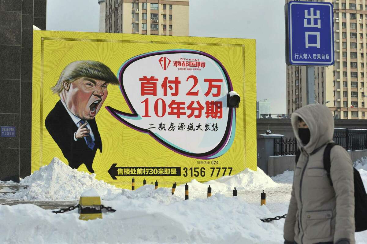 A pedestrian walks past a real estate advertisement featuring a cartoon figure resembling U.S. President Donald Trump in Shenyang in northeastern China's Liaoning province. China already a trademark for Trump-branded construction services on Feb. 14, the result of a 10-year legal battle that turned in Trump’s favor after he declared his candidacy.