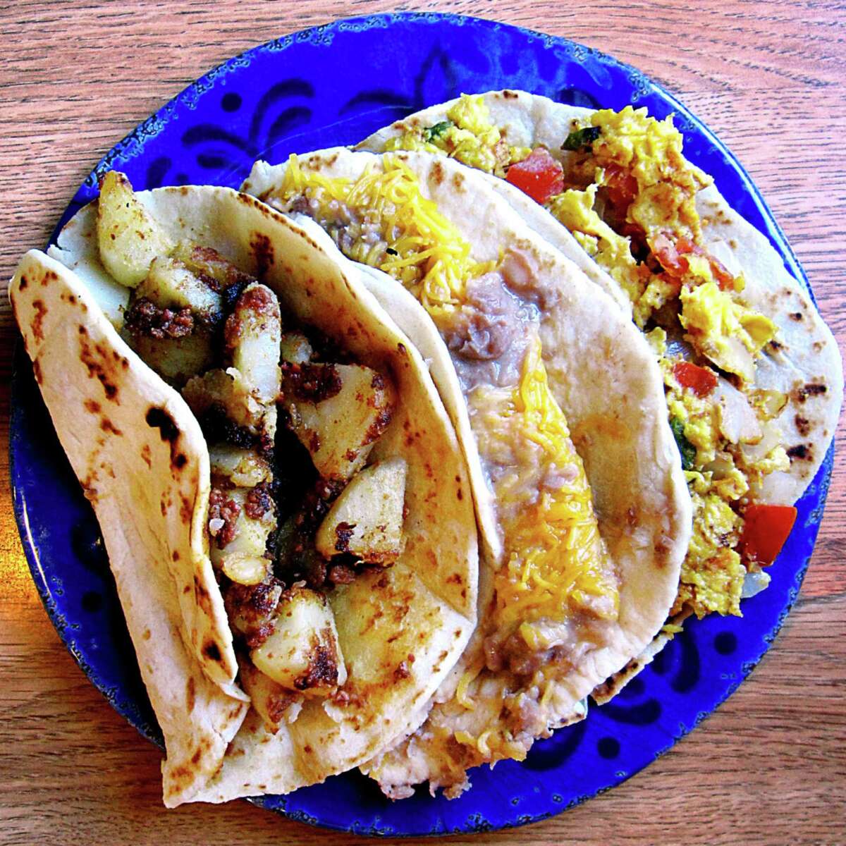 A trio of breakfast tacos on handmade flour tortillas. From left: potato and chorizo, bean and cheese and eggs a la mexicana from Taquería Guanajuato on Vine Street.