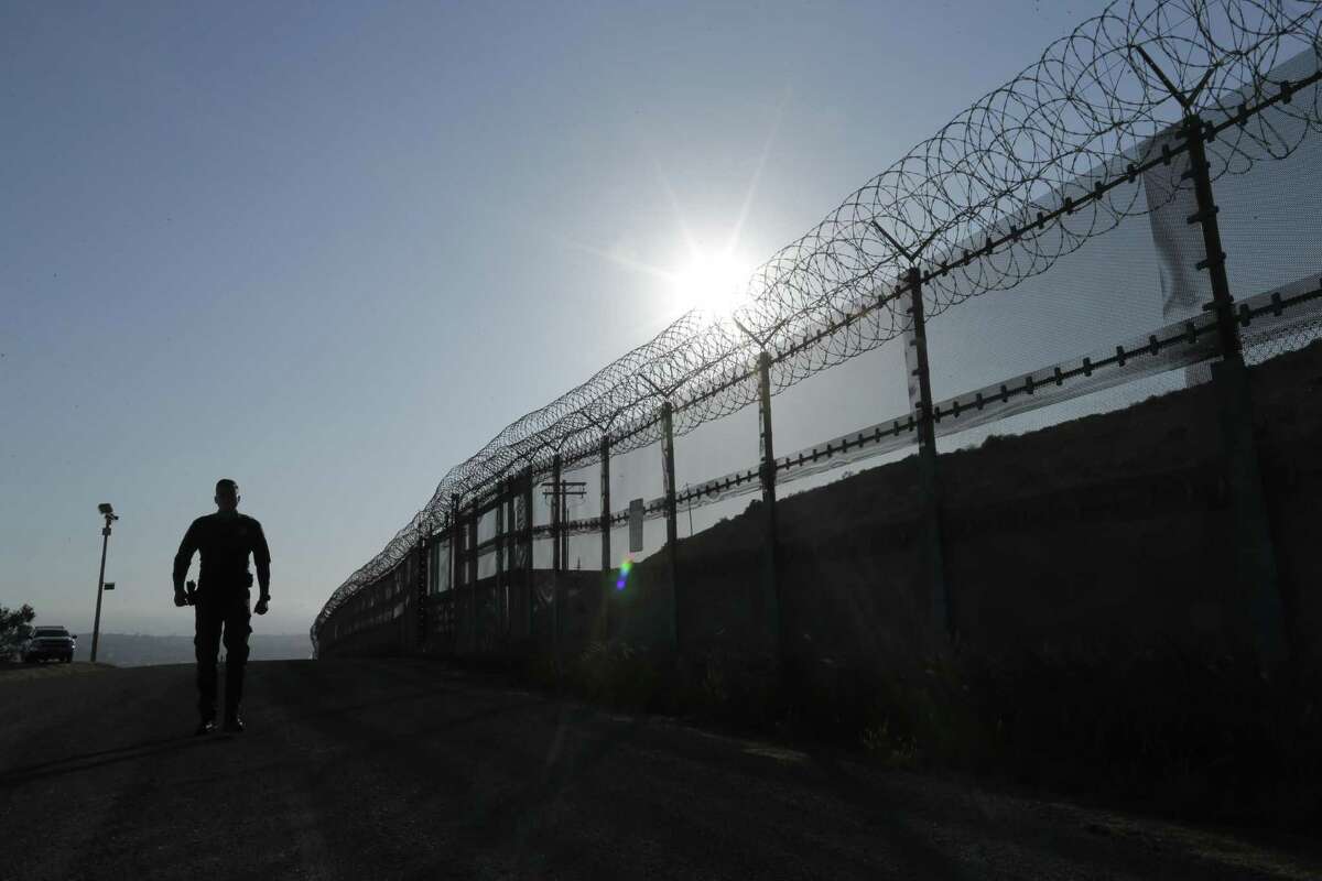 FILE--In this June 22, 2016, file photo, a Border Patrol agent walks along a border structure in San Diego, Calif. The U.S. Border Patrol's parent agency may exempt many veterans and law enforcement officers from a requirement that new hires take a lie-detector test. (AP Photo/Gregory Bull, file)