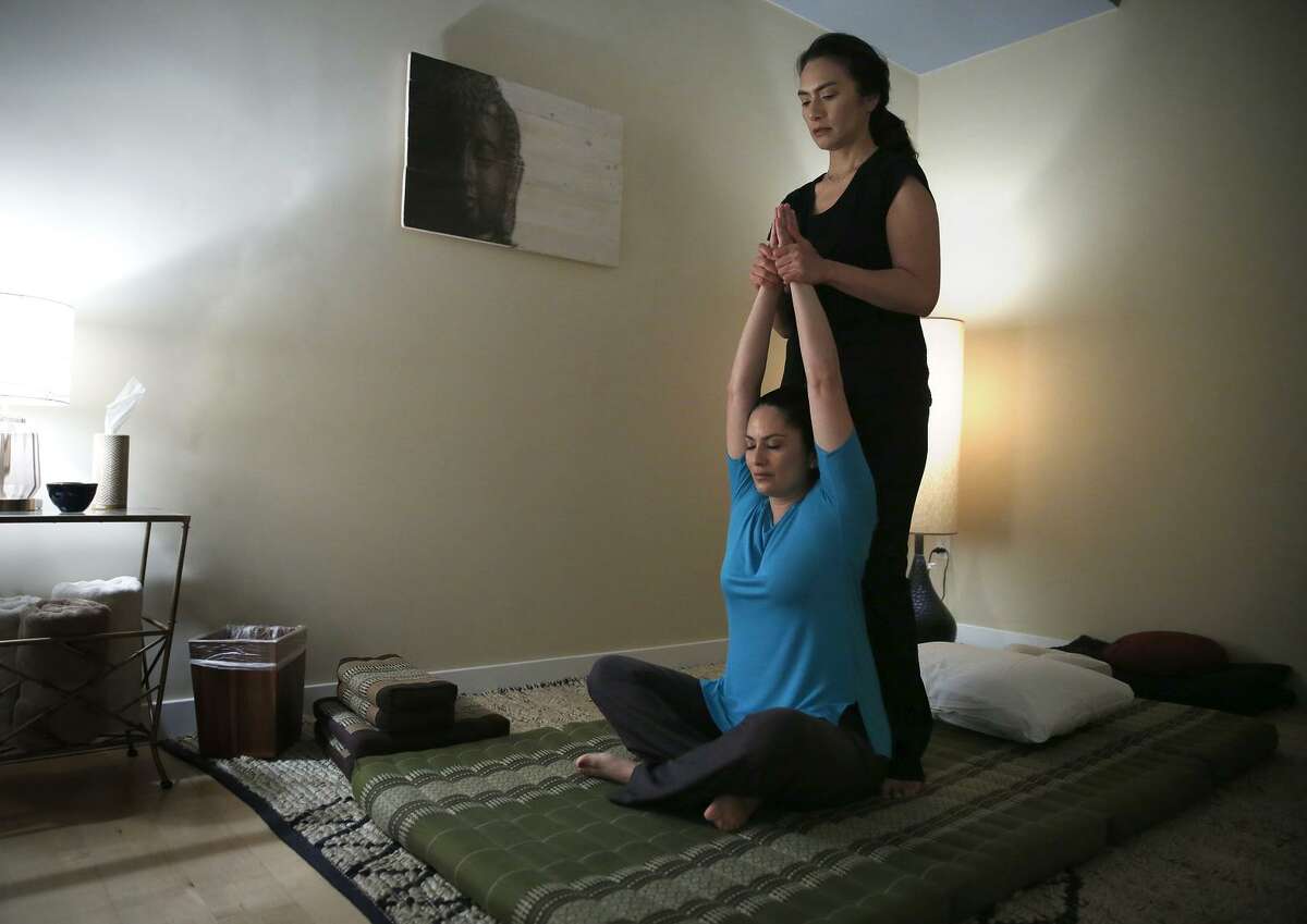 Upuia Ahkiong of Kua Body Studios stands as she gives massage therapist Jennifer Y. Ruiz a Thai massage in Los Altos.