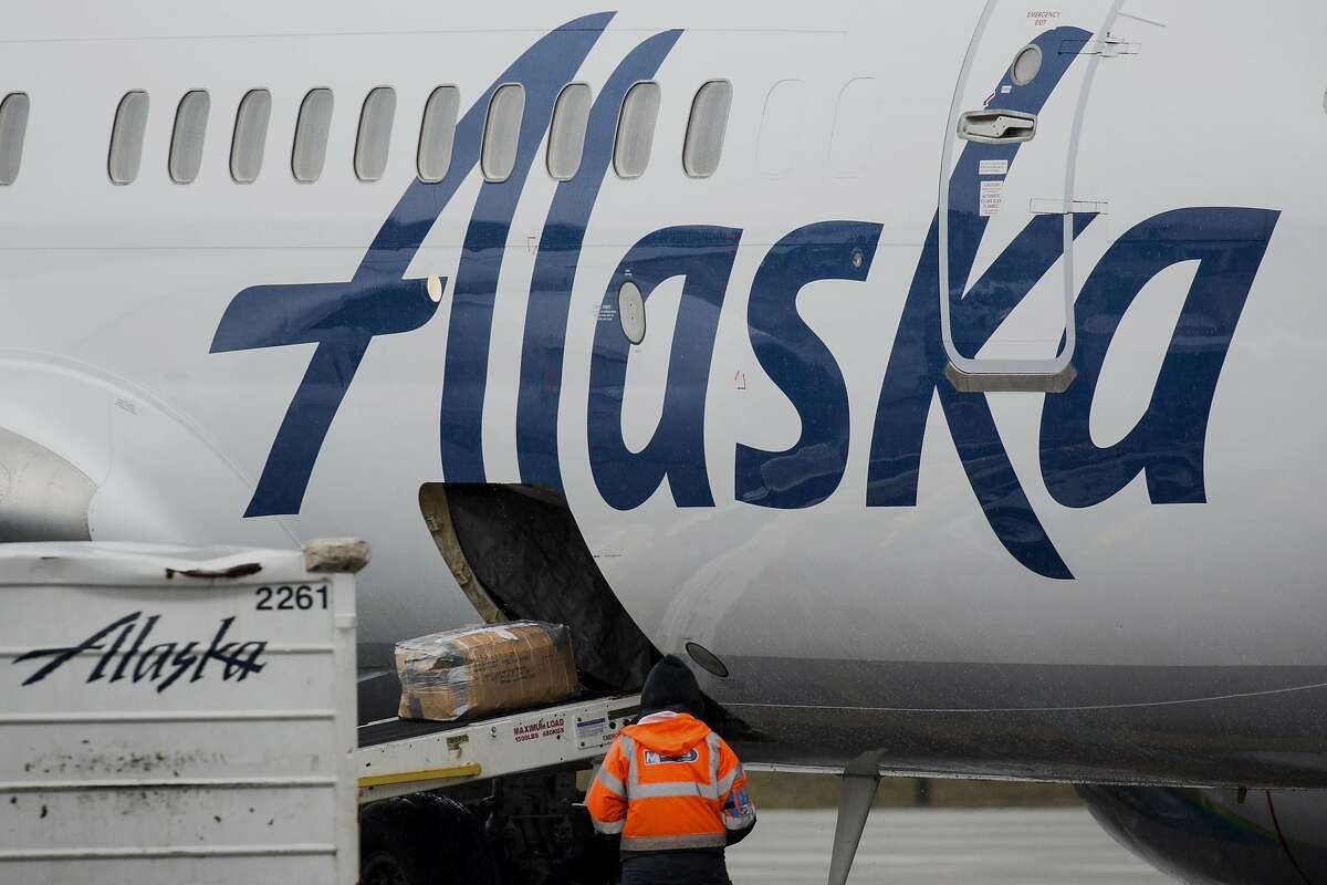 A worker watches baggage as it enters an Alaska Air Group Inc. jet at Seattle-Tacoma International (SEA) airport in Seattle, Washington, U.S., on Friday, Feb. 3, 2017. Alaska Air is expected to release earnings figures on February 8. Photographer: David Ryder/Bloomberg