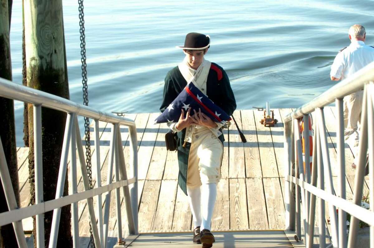Jonathan Hughes, 15, dressed in colonial garb carries the American Flag at the dockside Memorial Day ceremony at the Indian Yacht Club on Monday, May 31, 2010.