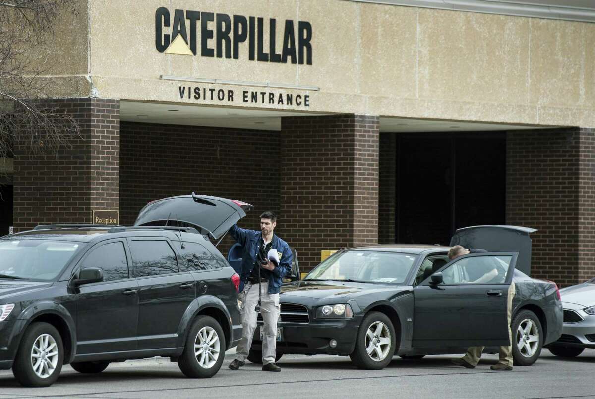 Federal officials gather at their vehicles on March 2 as they execute a search warrant at the Caterpillar Inc. facility in Morton, Ill.