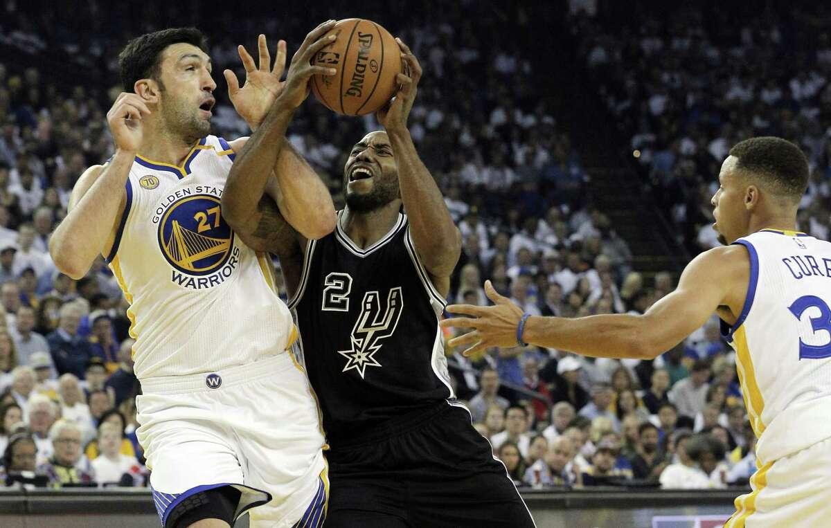Kawhi Leonard (2) drives into Zaza Pachulia (27) in the first half as the Golden State Warriors played the Spurs in the season opener at Oracle Arena in Oakland, Calif., on Oct. 25, 2016.
