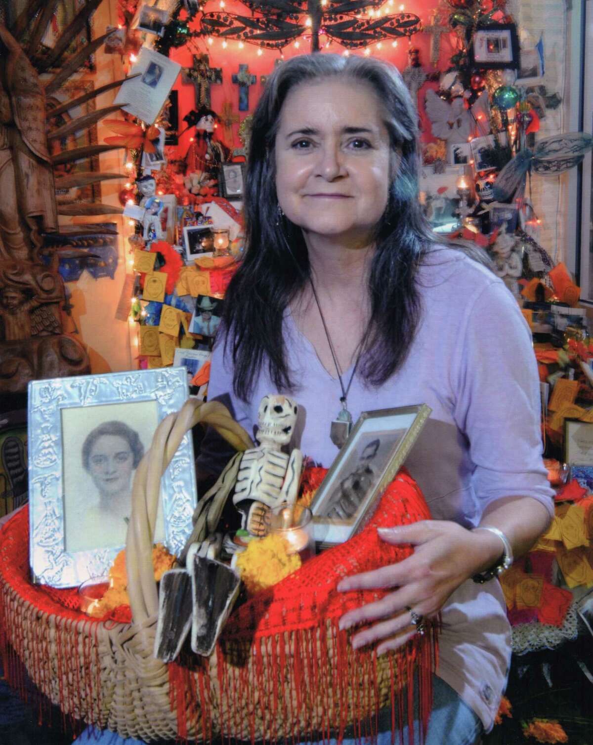 Mary Cerruti poses with a tribute she created for her parents as part of the annual Day of the Dead celebration at Casa Ramirez, a store where she occasionally worked. The store owners estimate the photo was taken around 2010. The basket contains images of her parents, a wood folk art skeleton, marigolds and small candles.