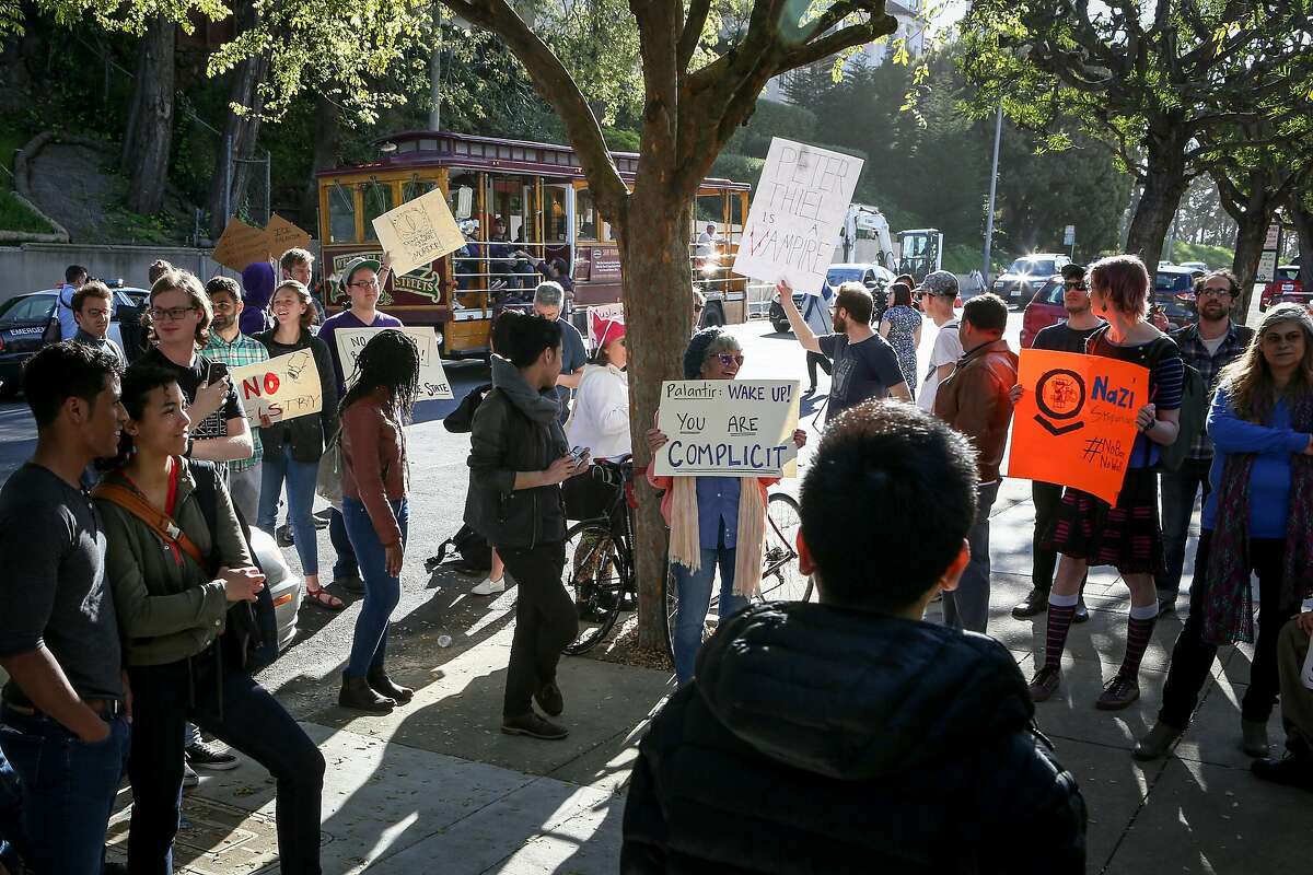 A tourist cable car drives past a protest in front of Palantir Technologies Inc. co-founder and chairman Peter Thiel's house on Saturday, March 11, 2017 in San Francisco, Calif.
