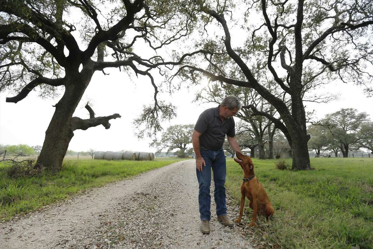 Atascosa County resident Russell Wilson stands on his property with his dog, Rider, on Tuesday, Feb. 28, 2017. The county is known for its loamy sand, good for growing peanuts, other legumes and strawberries. Now residents like Wilson are upset about a propsed frac sand mine that could be coming to their community. The mine's main site is located directly across a gravel road from Wilson's home. A Pennsylvania-based mining company about six months ago created an LLC in Texas and has targeted around 1,000 acres for a new mine. A group has organized in protest and so far the TCEQ has received 40 written protests and 163 public hearing requests. Atascosa County Judge Robert Hurley said he has told the mining company he doesn't want them there, but there's not much more the county can do, other than try to make it difficult for the company to run trucks 24 hours per day on its gravel roads. There's also a historic marker near the proposed site commemorating the Battle of Medina, the bloodiest conflict ever on Texas soil, whose precise location a mystery. Around 1,000 died in the early bid for Mexico's independence from Spain. The Republican Army of the North, including Tejanos and American Indians, was defeated by the Spanish Royal Army. The running battle lasted four hours and covered up to 8 miles, though no one has proven the precise location. Wilson along with fellow county resident Jessica Hardy, who are among the people living near the proposed sand mine, have organized a local group in trying to fight the permit. (Kin Man Hui/San Antonio Express-News)