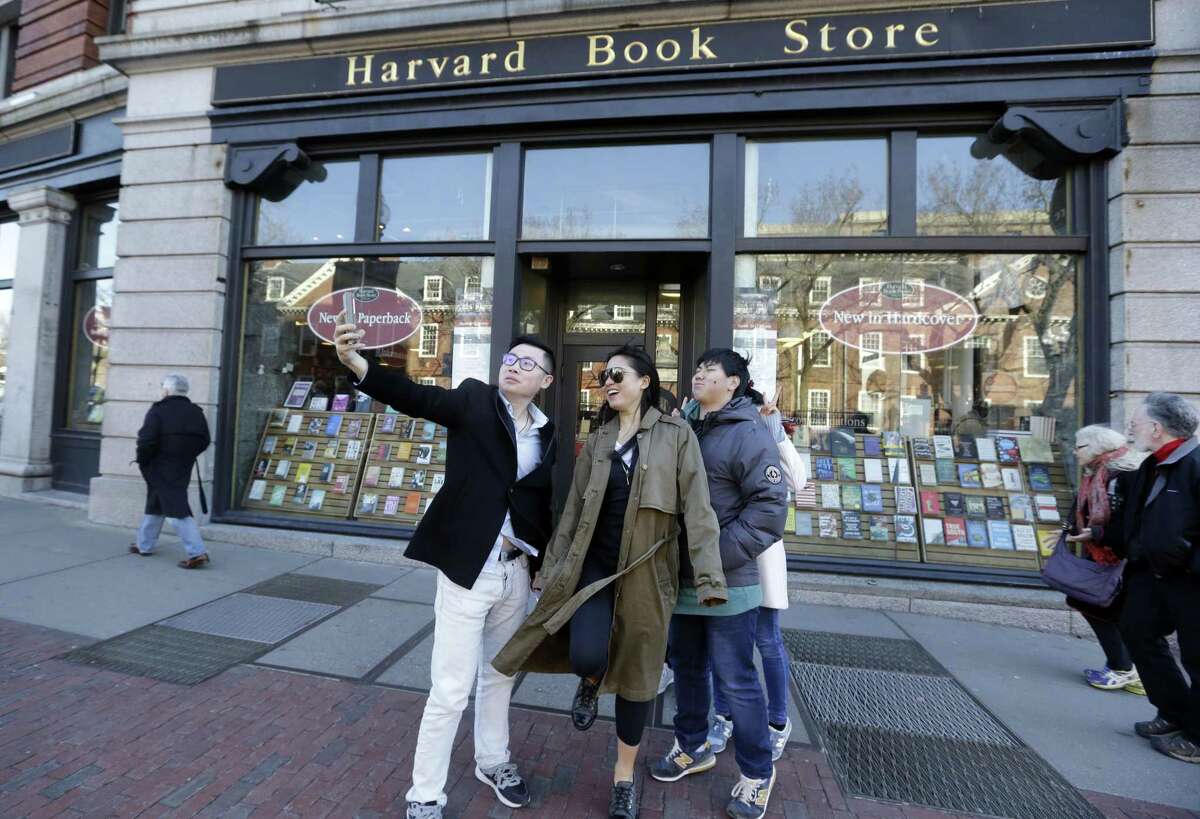 Students pose for a selfie outside the Harvard Book Store in Cambridge, Mass. Longtime staples in English literature courses, dystopian works are attracting new attention from casual readers and social book clubs. Local theater groups are adapting versions for the stage. College courses on dystopian classics are suddenly drawing long wait lists.