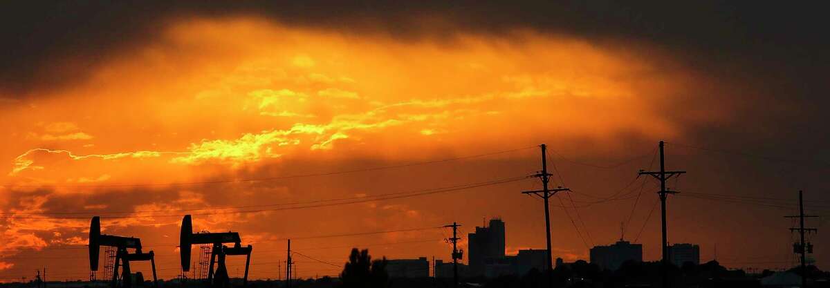 The sun sets behind the Midland skyline as pumpjacks work outside the city limits Thursday, Sept. 15, 2016. ( Michael Ciaglo / Houston Chronicle )