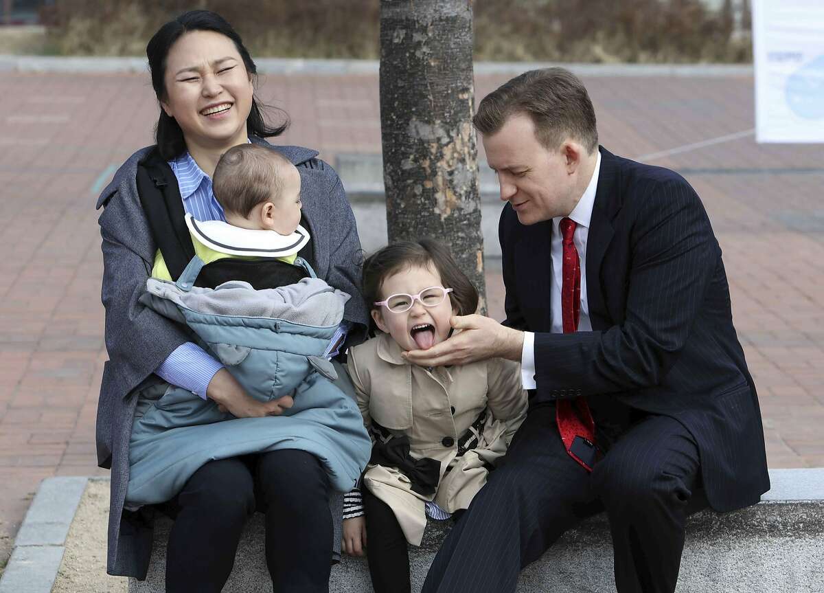 Robert Kelly, right, a political science professor at Pusan National University, waits for a press conference with his wife Jung-a Kim, left, and children James and Marion, at the university in Busan, South Korea, Wednesday, March 15, 2017. As Kelly speaks from his home office via Skype with BBC about the just-ousted South Korean president, his eyes dart left as he watches on his computer screen as his young daughter parades into the room behind him. Her jaunty entrance resembles the exuberant march of the Munchkins celebrating the Wicked Witch's death in the "The Wizard of Oz." (Ha Kyung-min/Newsis via AP)