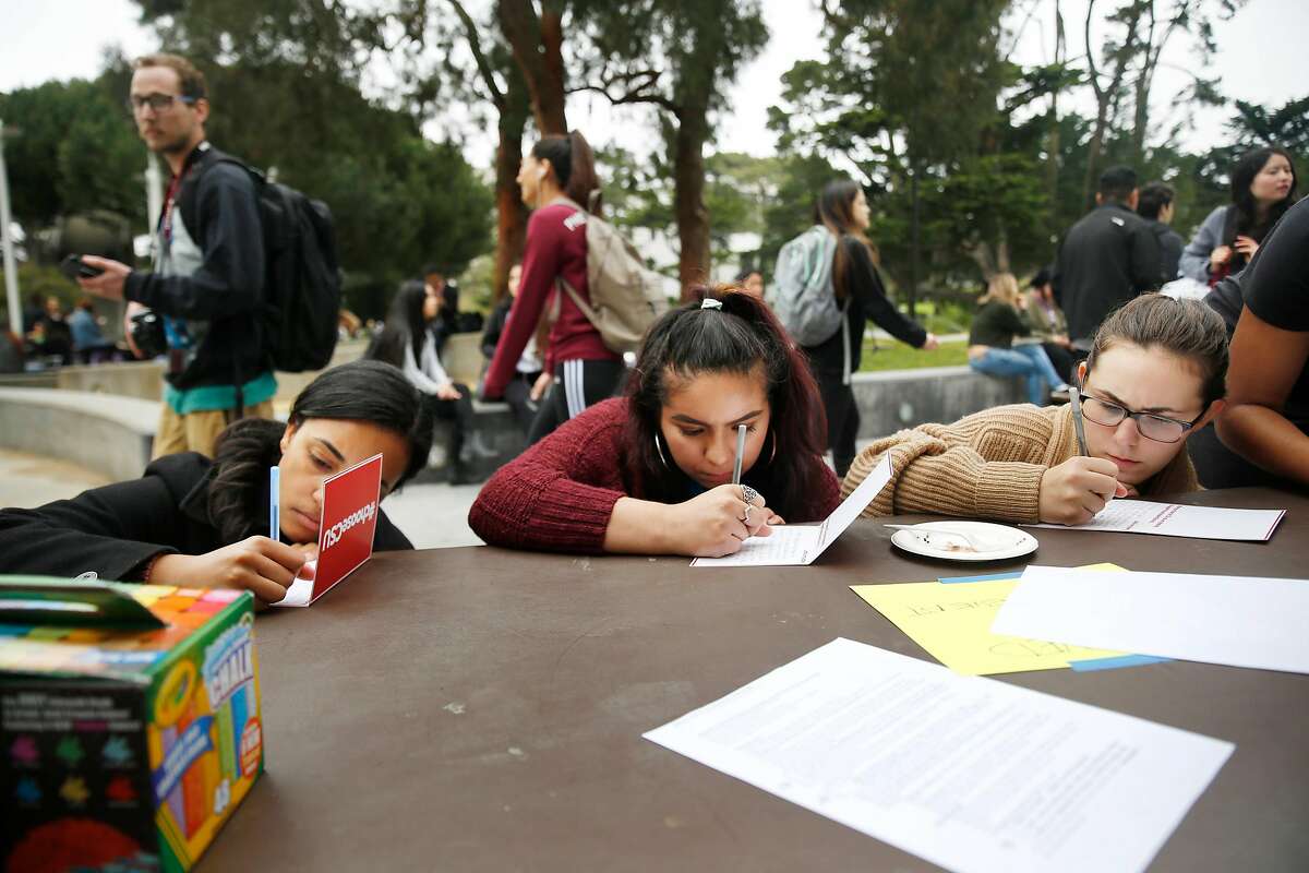 Ashley Sarkodie, graduate of CSU Fullerton; Alejandra Mendez-Ruiz, SFSU student and Jordan Zabek, SFSU student, fill out cards during an anti tuition increase demonstration at San Francisco State University on Wednesday, March 15, 2017 in San Francisco, Calif.