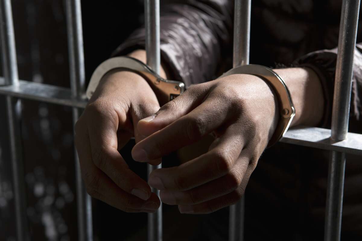 This Getty stock images show a handcuffed man with his hands sticking out of the bars of a jail cell. 