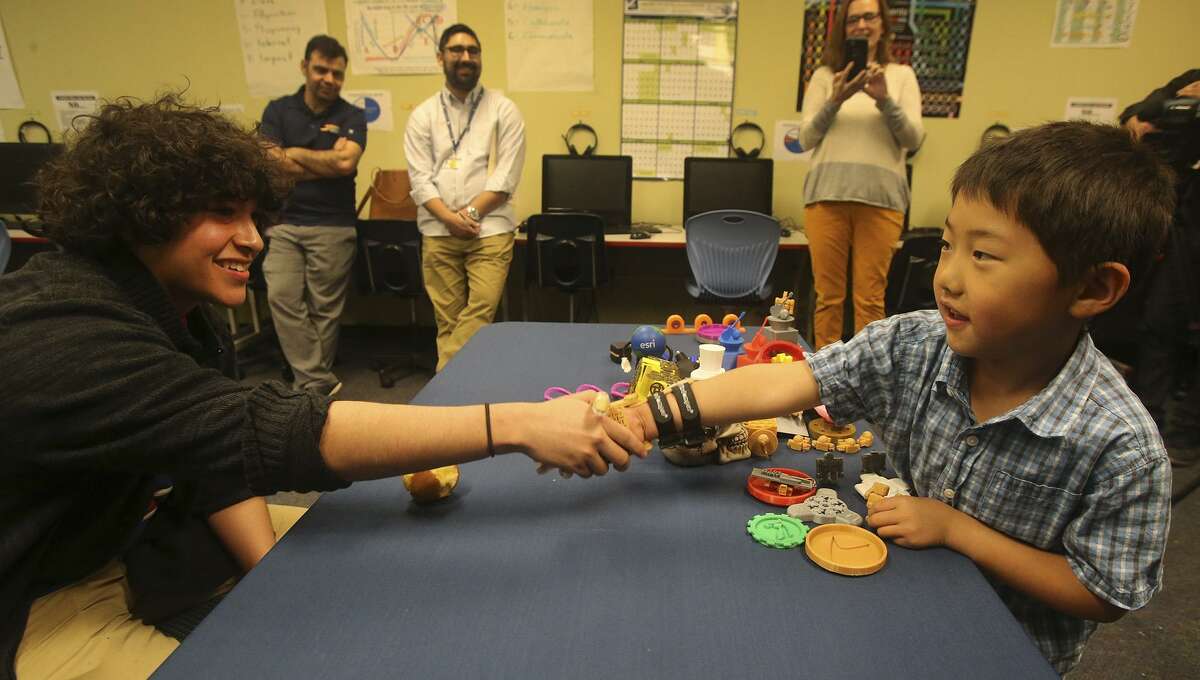 Zack Robbins,6, (right) uses a prosthetic hand Wednesday March 8, 2017 to shake hands with School of Science and Technology student Justin Cantu,16 (left). Robbins was born with underdeveloped right hand and Cantu used technology created by an on-line community called e-NABLE to make the hand for Robbins with a 3D printer.