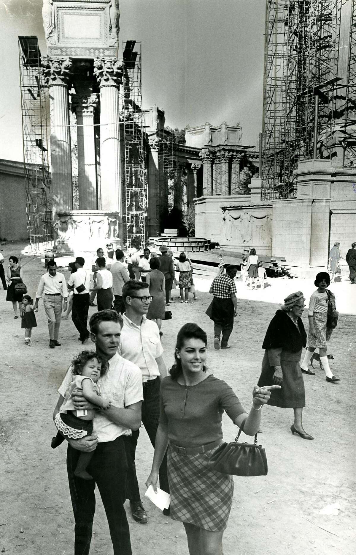 Mr. and Mrs. Roger Sigenar with their daughter, with crowd checking out the reconstruction and restoration of the San Francisco Palace of Fine Arts. October 30, 1966