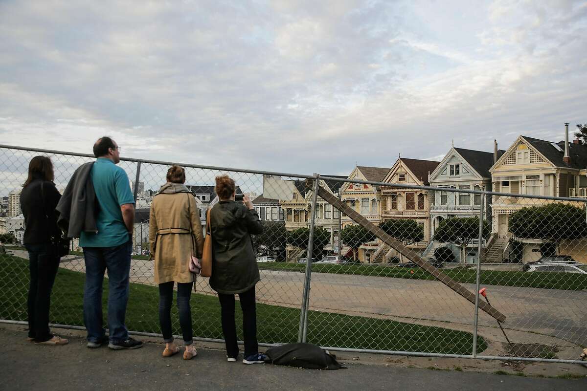 (l-r) Tourists Katie Johnson, Rob Johnson, Leah Johnson and Karen Johnson who are visiting from Austin, Texas, look at the Painted Ladies through fencing which is blocking off Alamo Square Park while it undergoes construction in San Francisco, California, on Wednesday, March 15, 2017.