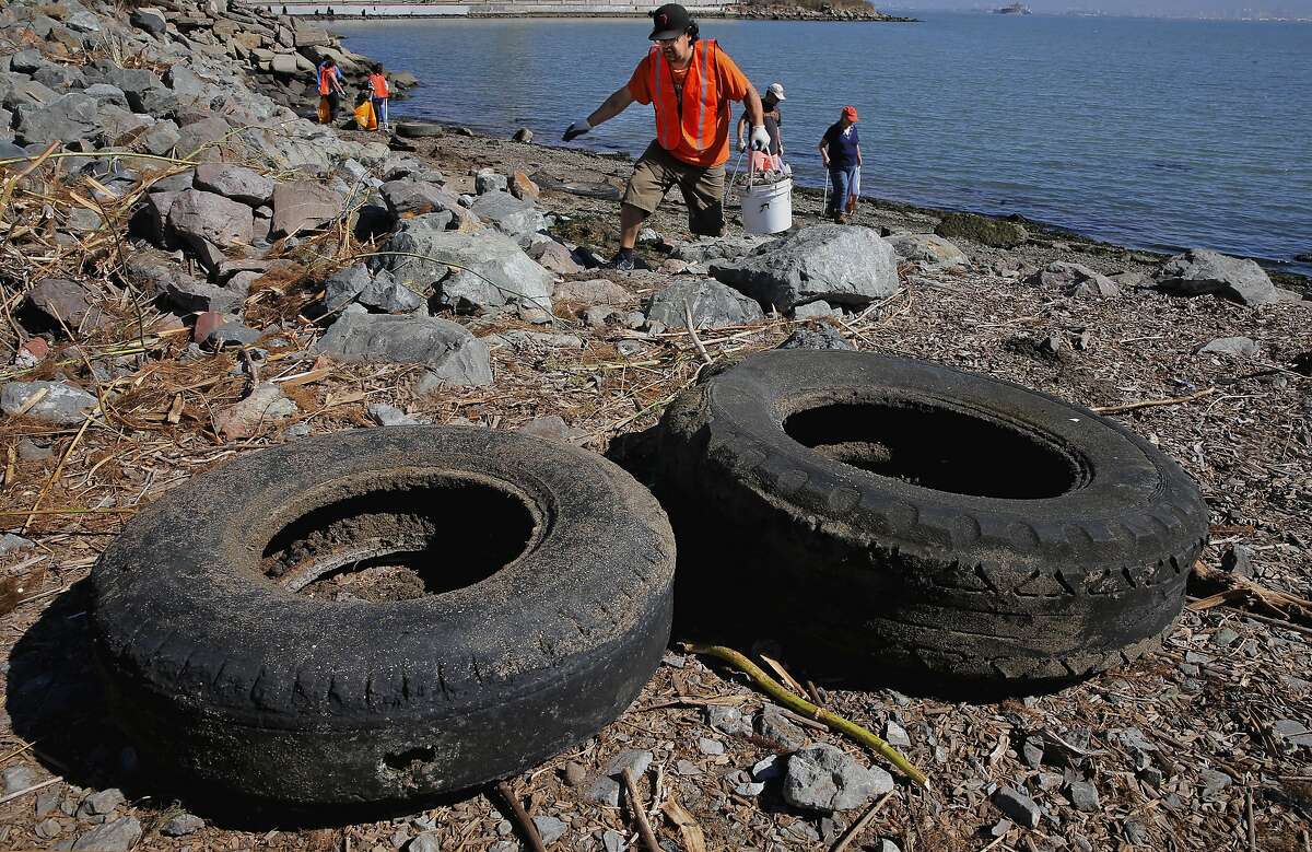 Jorge Gonzalez, searches for debris near collected old tires at Warm Water Cove, in San Francisco, Calif., as he joins hundreds of volunteers participating in the Community Team's Coastal Cleanup Day, at different locations along the San Francisco Bay shoreline, on Sat. September 19, 2015.