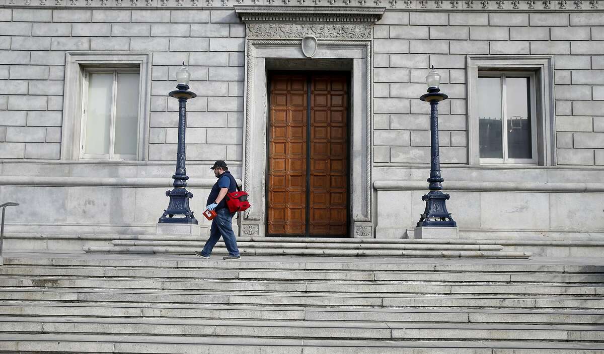 Jose Luis Guzman, from the Department of Public Health, looks for discarded hypodermic needles on the steps of the Asian Art Museum in San Francisco, Calif. on Thursday, March 16, 2017.