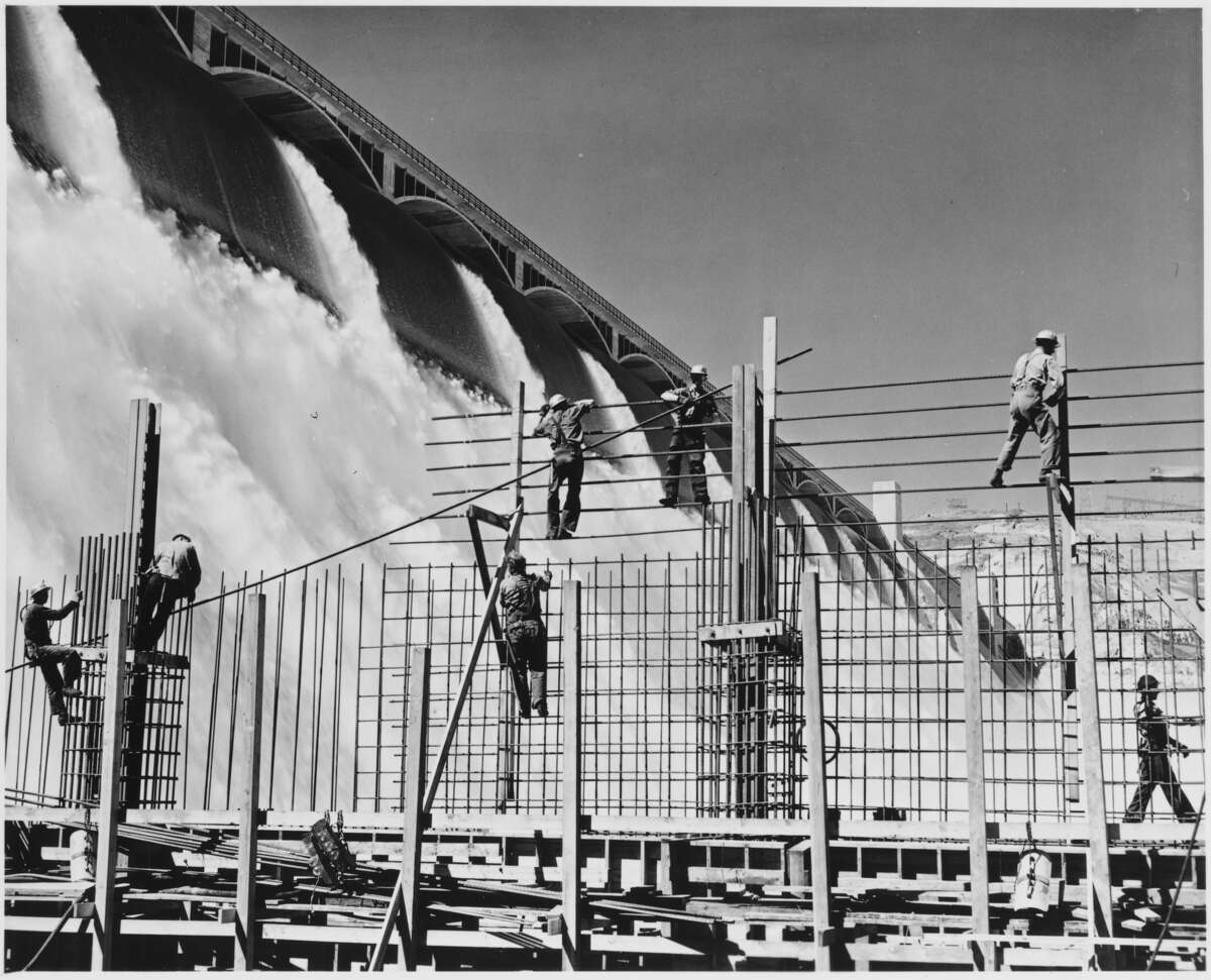 Workers construct a rebar structure as the Columbia River cascades over an enormous spillway at the Grand Coulee Dam. Washington, USA, 1936-1946. | Location: Washington, USA. (Photo by Library of Congress/Corbis/VCG via Getty Images)