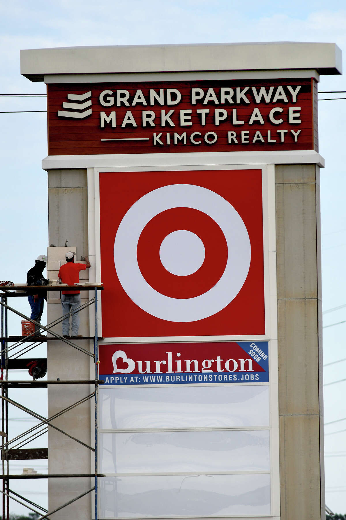 Workers put the finishing touches on a sign at Grand Parkway Marketplace I.