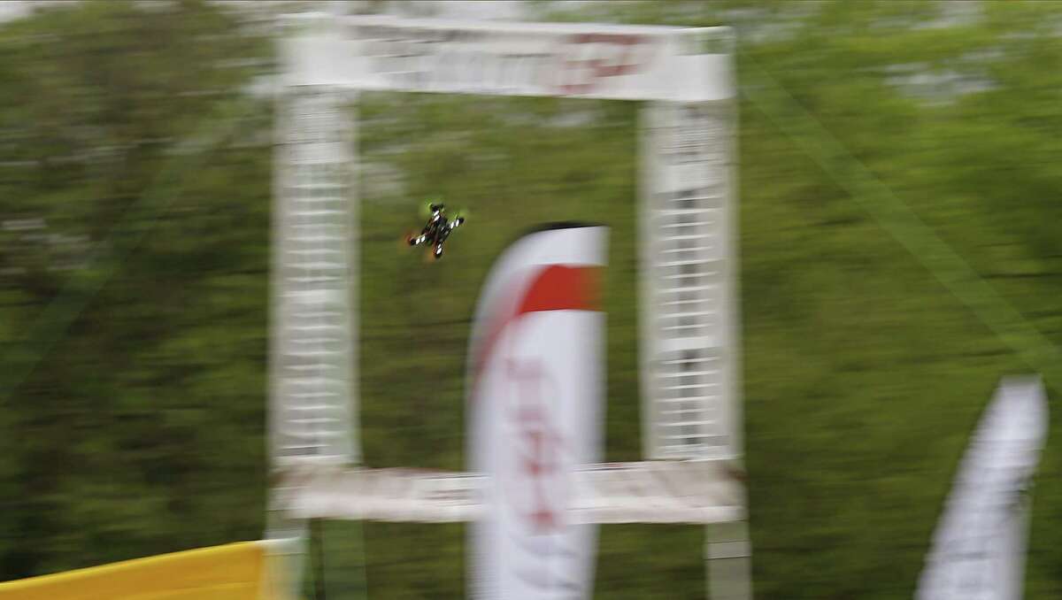 A drone zips through an obstacle as drone racers from the area gather at Solms Park in New Braunfels, Texas for a competition qualifier on Saturday, Mar. 18, 2017. With their toolboxes, extra batteries and a cornucopia of drone parts, competitors practiced their best routes around a course of dips, dives and challenging obstacles before starting the qualifying rounds. With speeds reaching 70-80 miles per hour, racers rely on a good signal through their video FPV (first person view) googles and their cat-like reflexes to remotely fly the drones along the course. (Kin Man Hui/San Antonio Express-News)