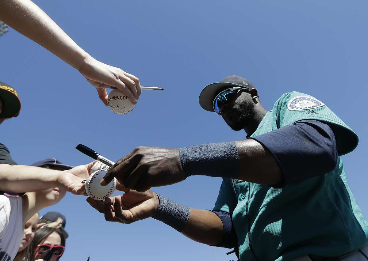 Seattle Mariners' Guillermo Heredia gives autographs before a spring training baseball game against the Texas Rangers, Sunday, March 19, 2017, in Surprise, Ariz. (AP Photo/Darron Cummings)